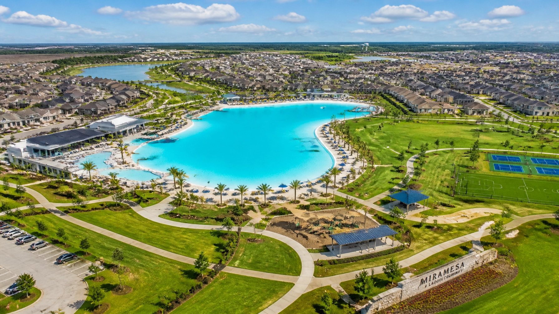 Aerial drone shot of a sprawling Houston master-planned community with a crystal lagoon