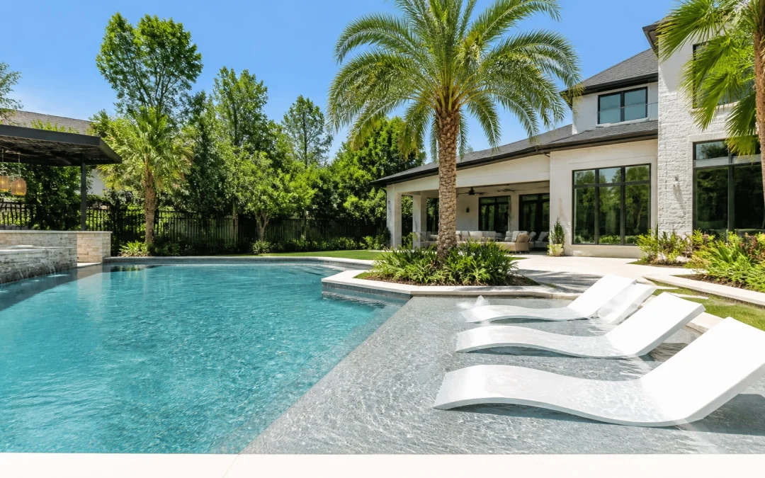 A high-end luxury swimming pool in a Houston suburban backyard during a bright, sunny June day