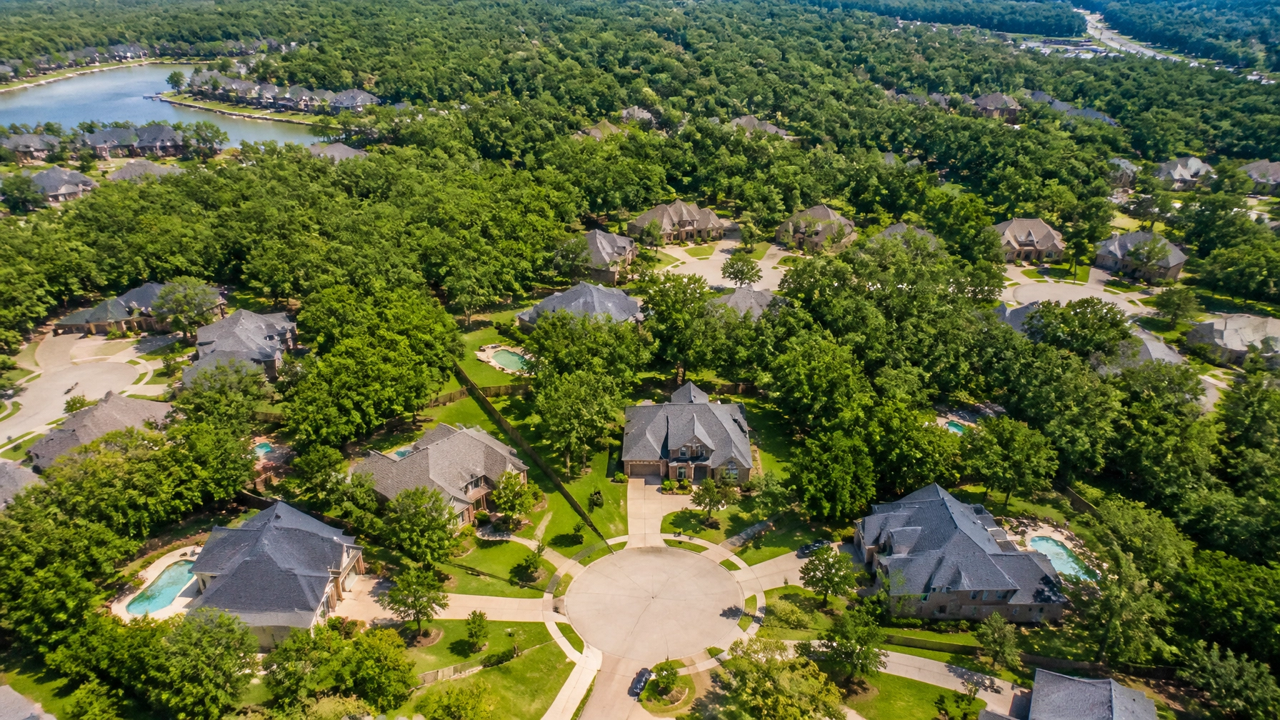 A bird's-eye view of a beautiful, leafy Houston suburb with modern houses and swimming pools