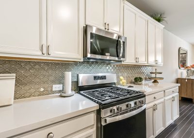Modern kitchen with stainless steel appliances and stylish tile backsplash, featured property in Katy, Texas.