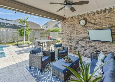 Outdoor patio area with seating and television in Katy, Texas property listing.