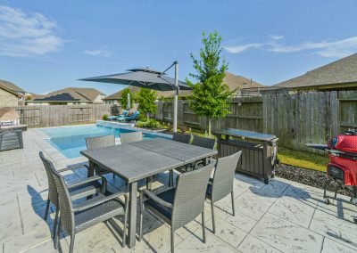 Backyard patio with pool and dining area for Katy, Texas property listing.