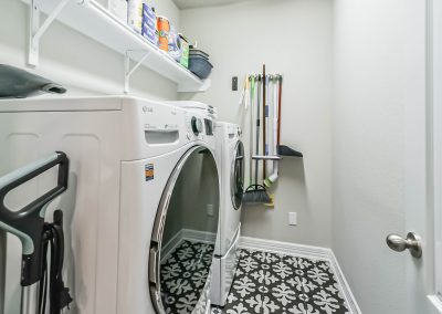 Laundry room with washer, dryer, and storage shelves in Katy, Texas home for sale.