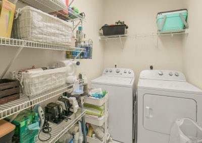 Organized laundry room with shelving and stacked washer and dryer in Katy, Texas home.