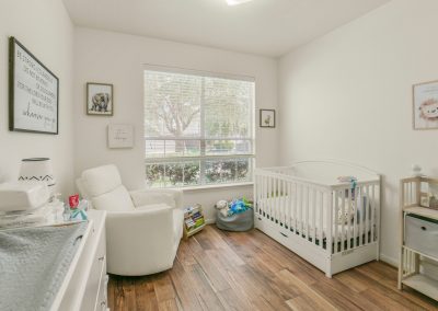 Bright Katy Texas home interior featuring a nursery with a crib and rocking chair.