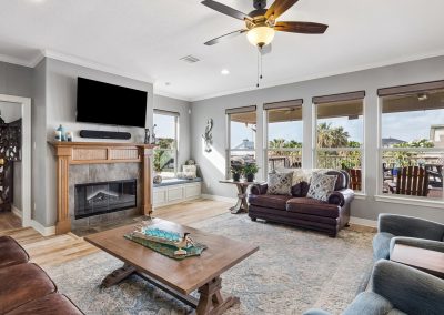Living room interior with fireplace, large windows, and modern furnishings for sale in Galveston, Texas.