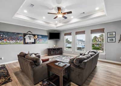 Luxurious living room with recessed lighting, ceiling fan, and framed artwork in Galveston, Texas property.