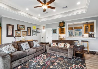 Living room interior with ceiling fan, artwork, and view of kitchen in Galveston, Texas property.
