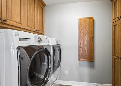 Laundry room with wooden cabinetry and modern appliances in Galveston, Texas property.
