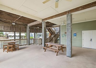 Covered outdoor patio with picnic tables and stairs, Galveston Texas property for sale by Bexley Realty Group.