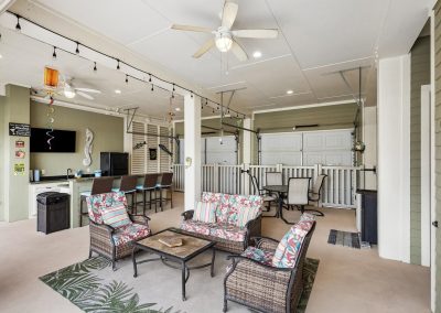 Covered patio with seating area, outdoor kitchen, and garage in Galveston, Texas property.
