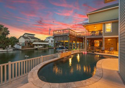 Luxury waterfront home in Galveston, Texas with pool and boat dock at sunset